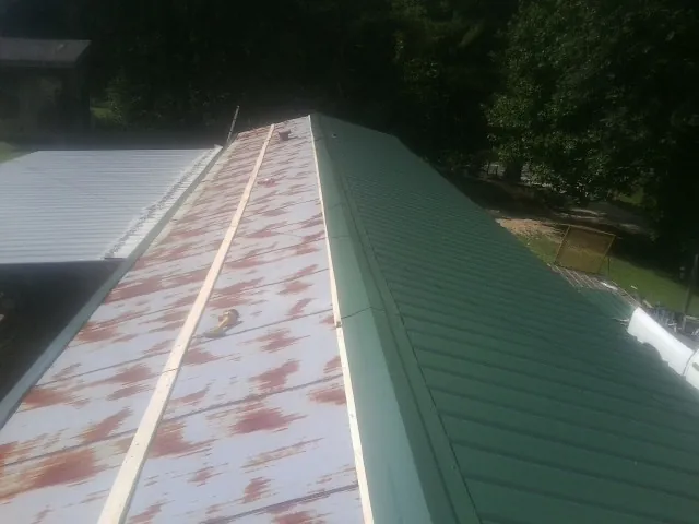 Old rusted panels beside newly installed green metal roofing — Wind Damage Roof Repair by Roofing Brothers in Whites Creek