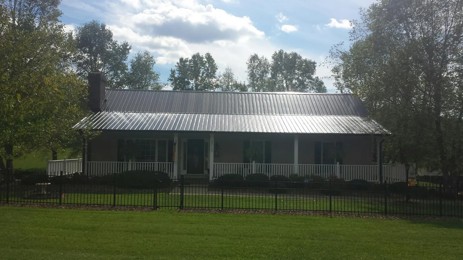 Gray metal roof on a brick ranch with a full width front porch — Gutter Guard Installation work by our crew in Whites Creek