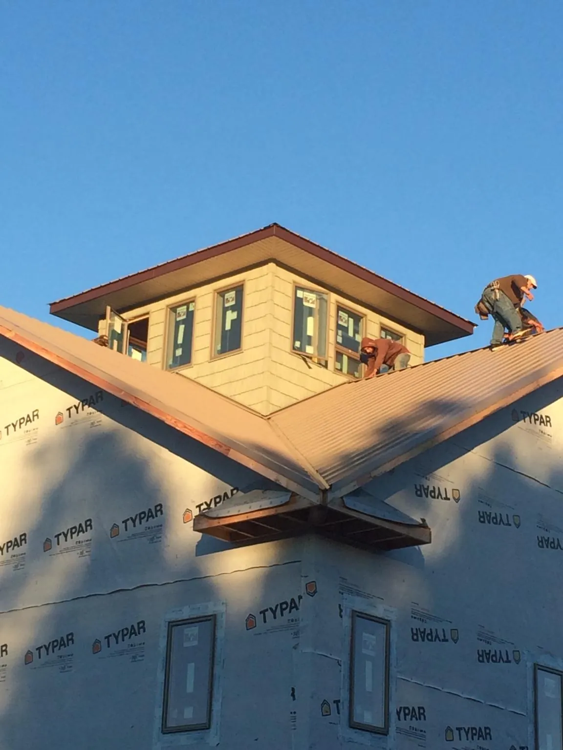 Roofers working around a rooftop cupola on a new metal roof at sunset — Roof Waterproofing in Whites Creek by Roofing Brothers